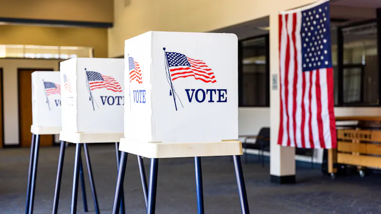 Three voting booths and an American flag.