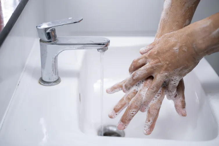 Close-up of sudsy hands being washed over a sink