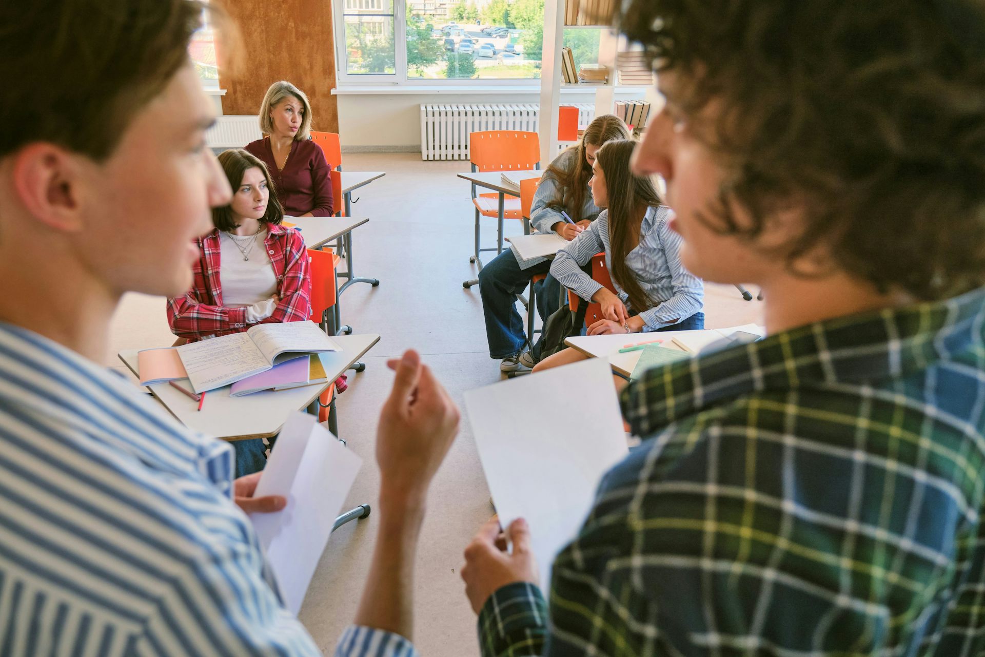 Two students in tense dialogue at the front of a room.