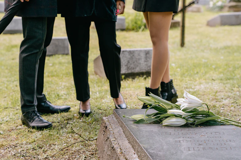 Mourners dressed in black pay respects to a grave.