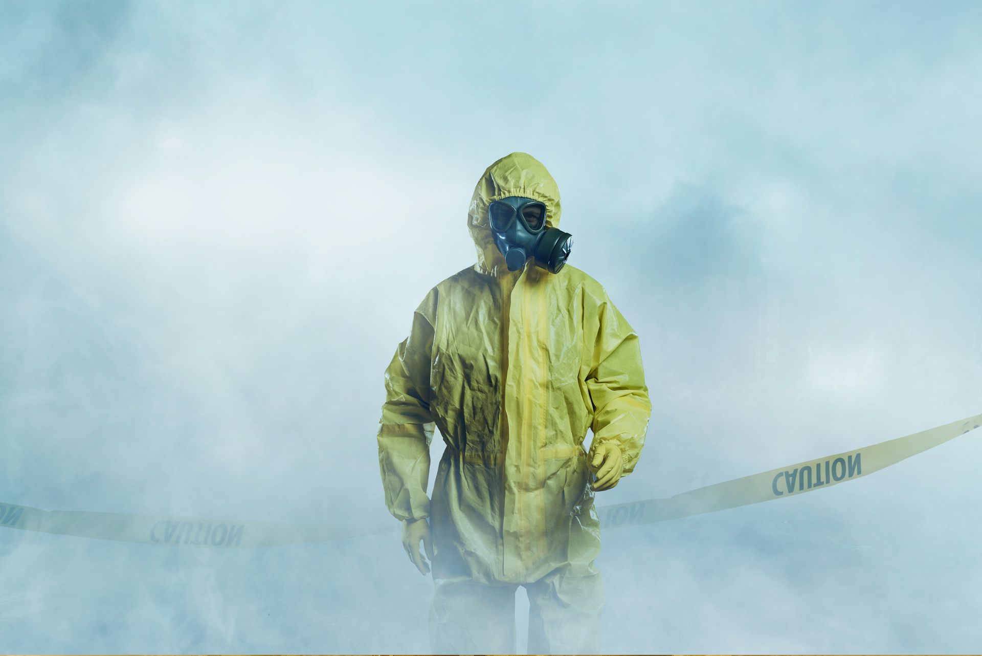 Worker wearing yellow protective suit walking in fog.