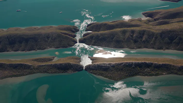 An aerial view of fast-flowing water between a narrow channel.