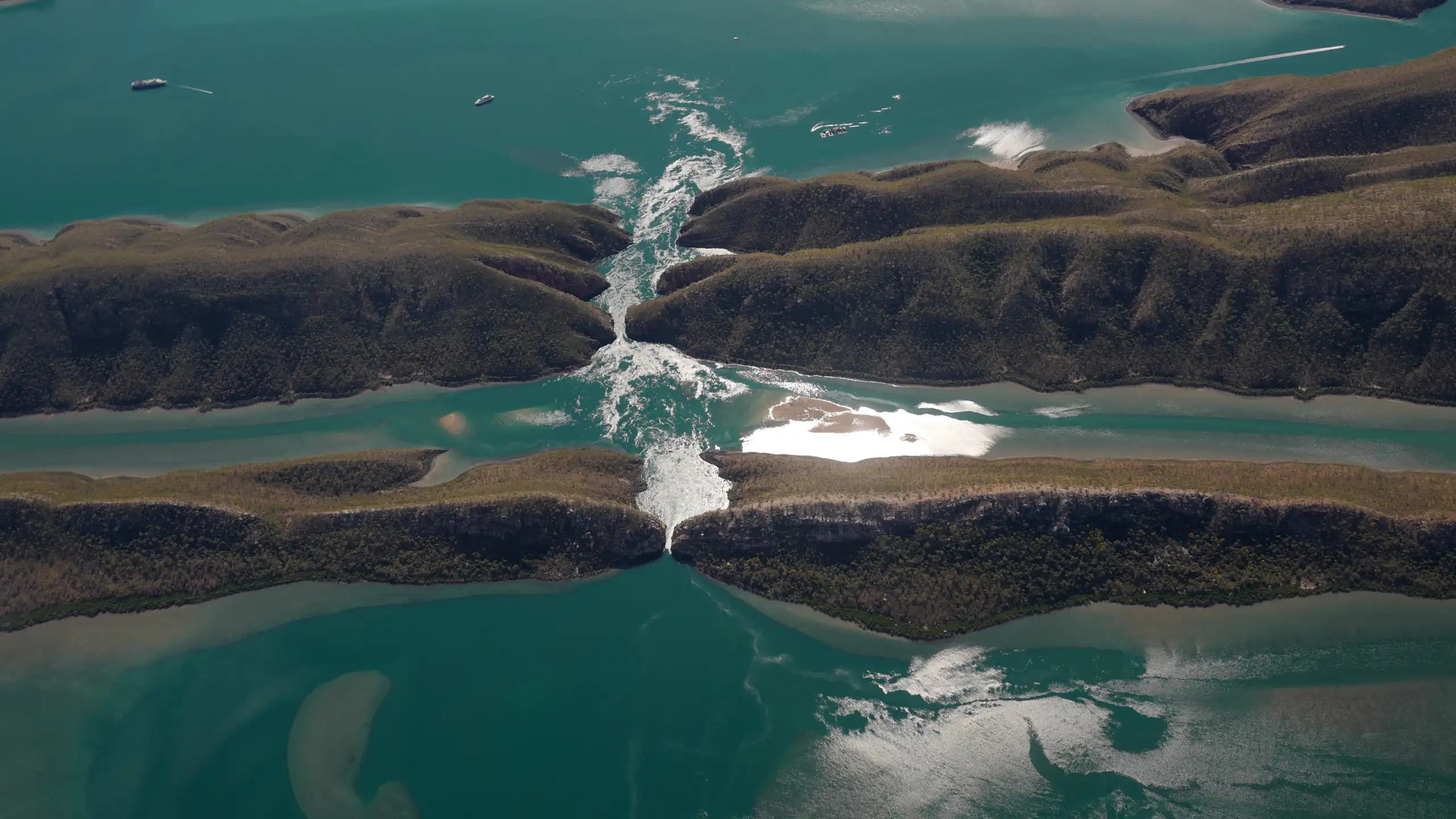 An aerial view of fast-flowing water between a narrow channel.