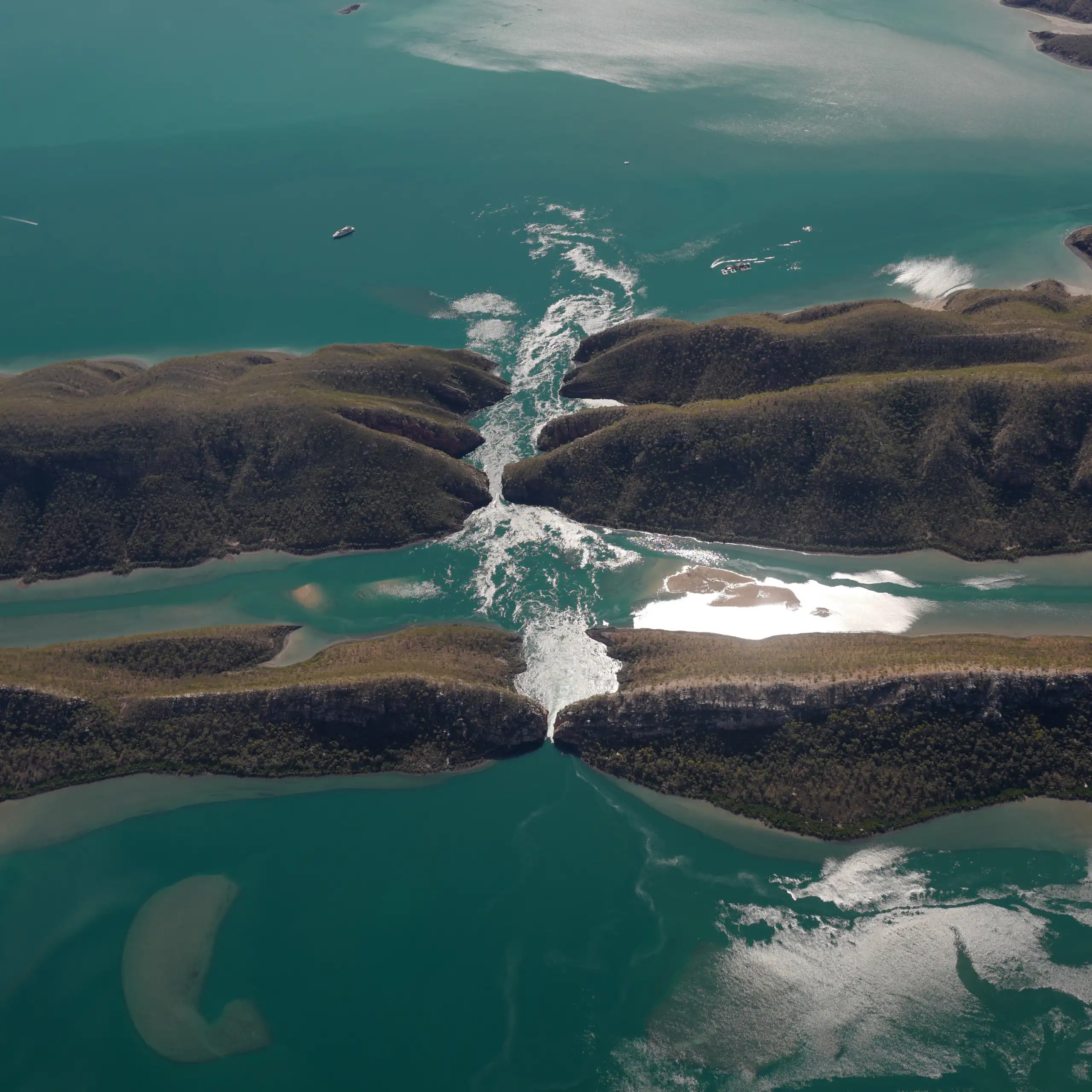 An aerial view of fast-flowing water between a narrow channel.
