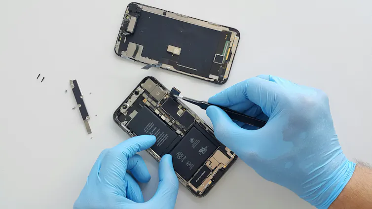 A smarthphone with the back taken off is being repaired.