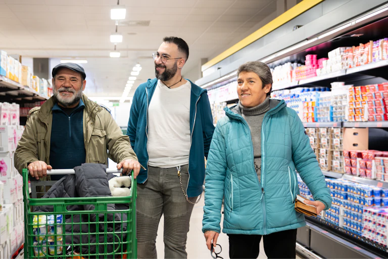 trois personnes deux hommes (un jeune et un plus âge) et une femme déambulent dans les rayons d'un supermarché.