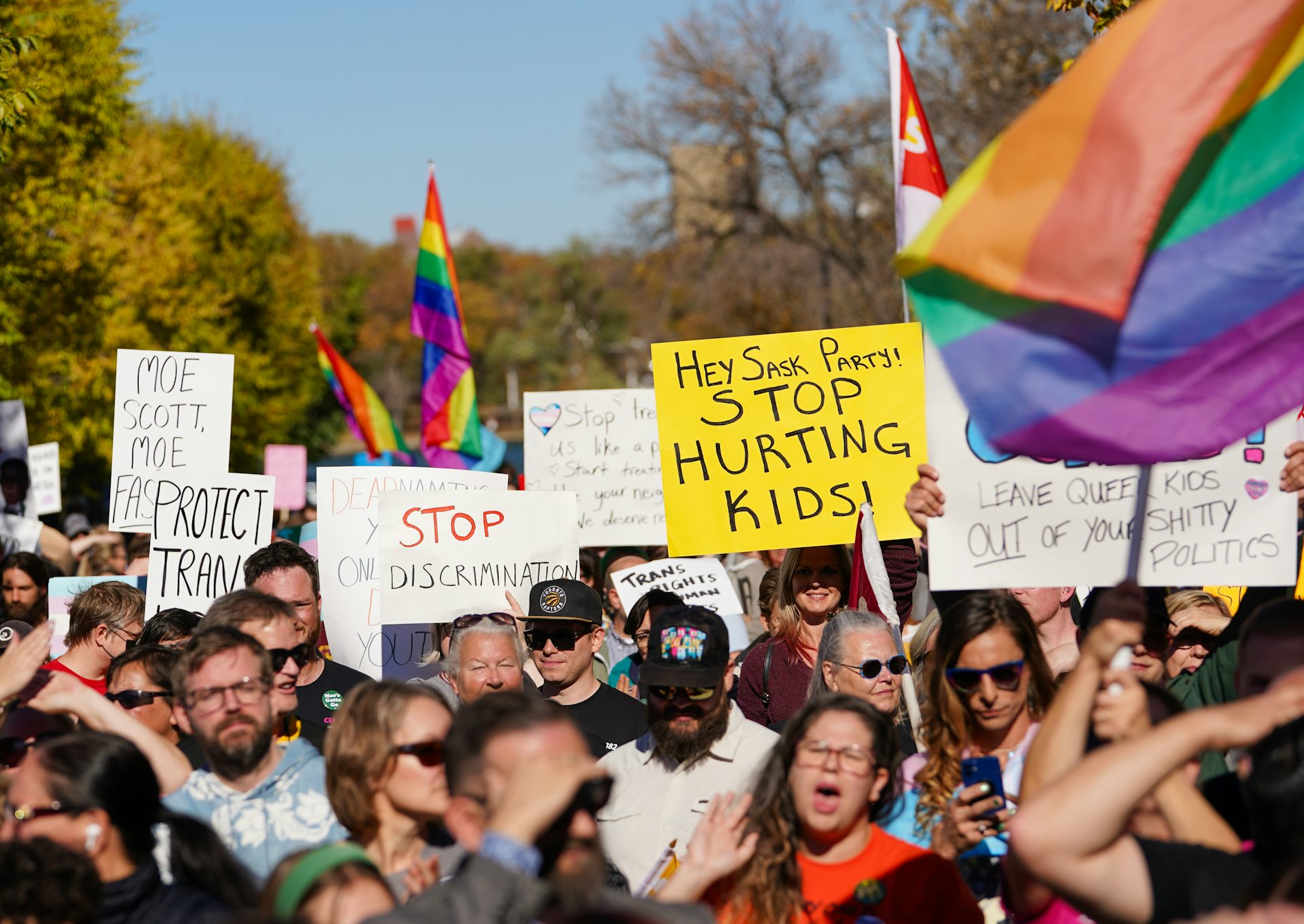 People hold rainbow flags in front of a domed building.