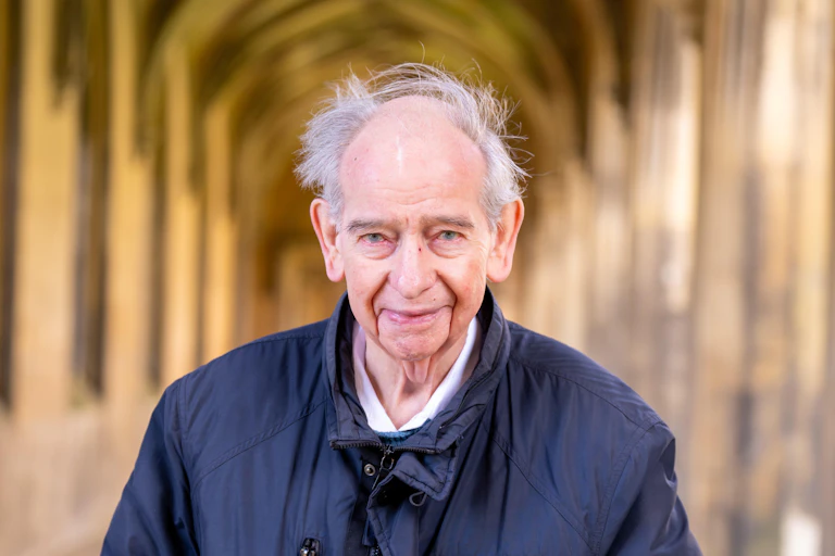A man facing the camera, with a blurred hallway background