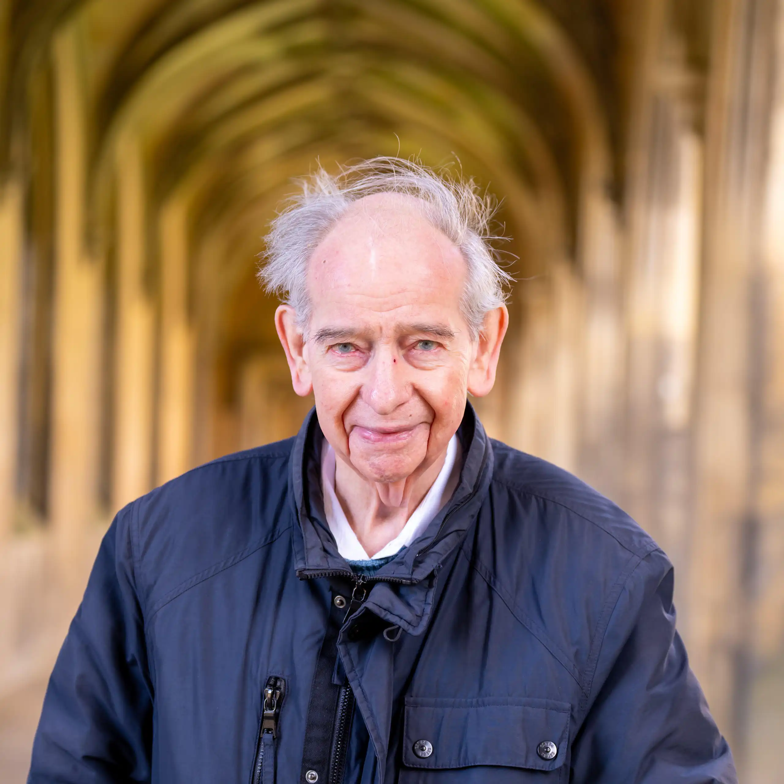 A man facing the camera, with a blurred hallway background