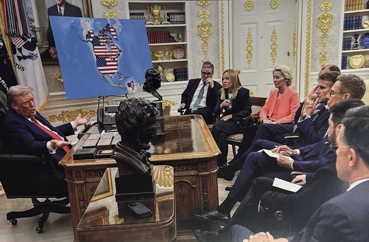 People in an office look at a map of North America with the U.S. flag super-imposed on it.