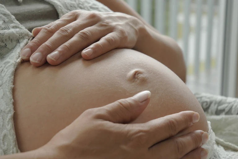 A woman holds per pregnant belly