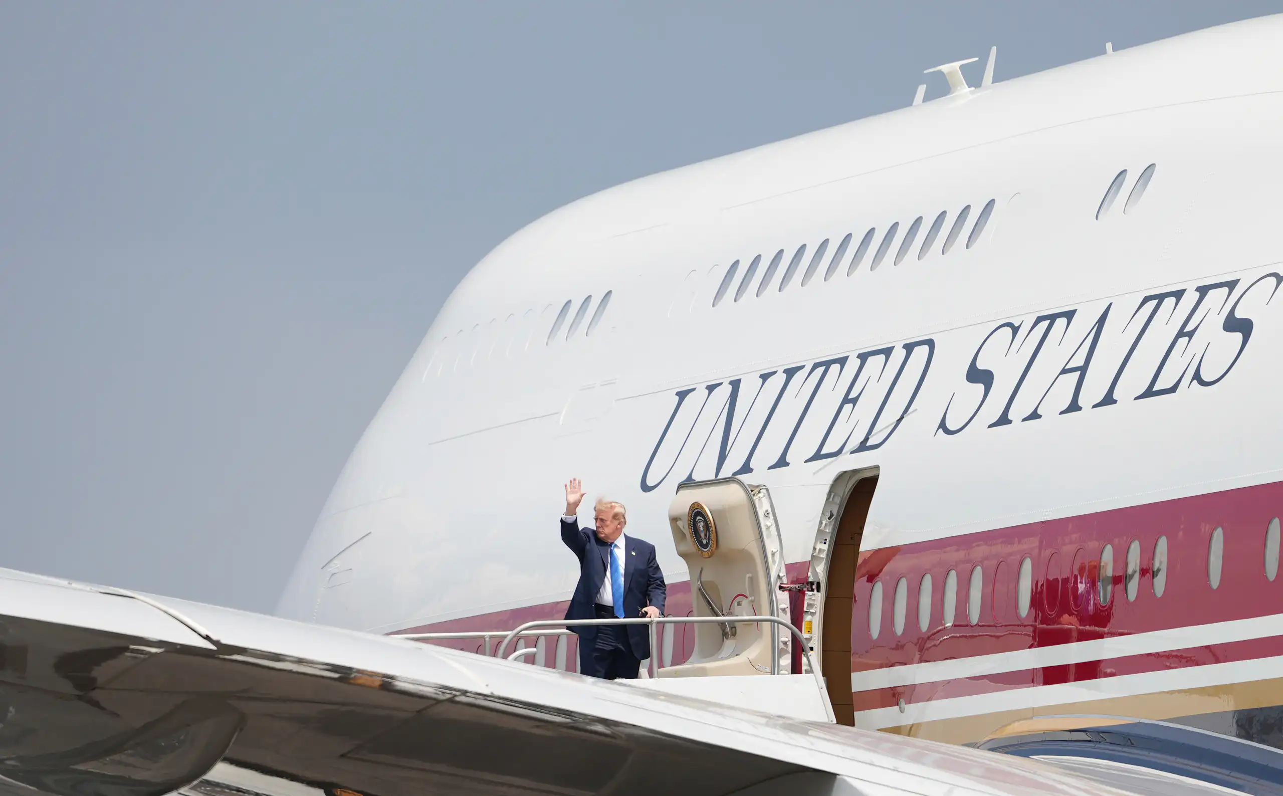 A rotund man waves as he gets into a large jet with United States emblazoned on its fuselage.