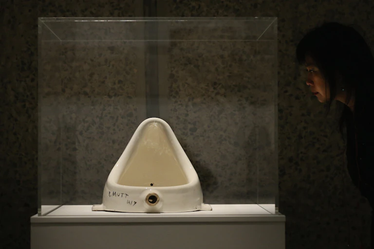 A white urinal behind a glass case