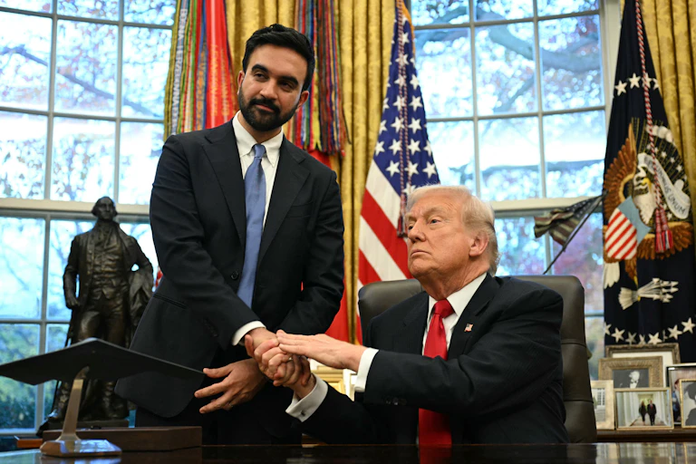 Donald Trump, ,assis à son bureau, serre la main de Zohran Mamdani, resté debout.