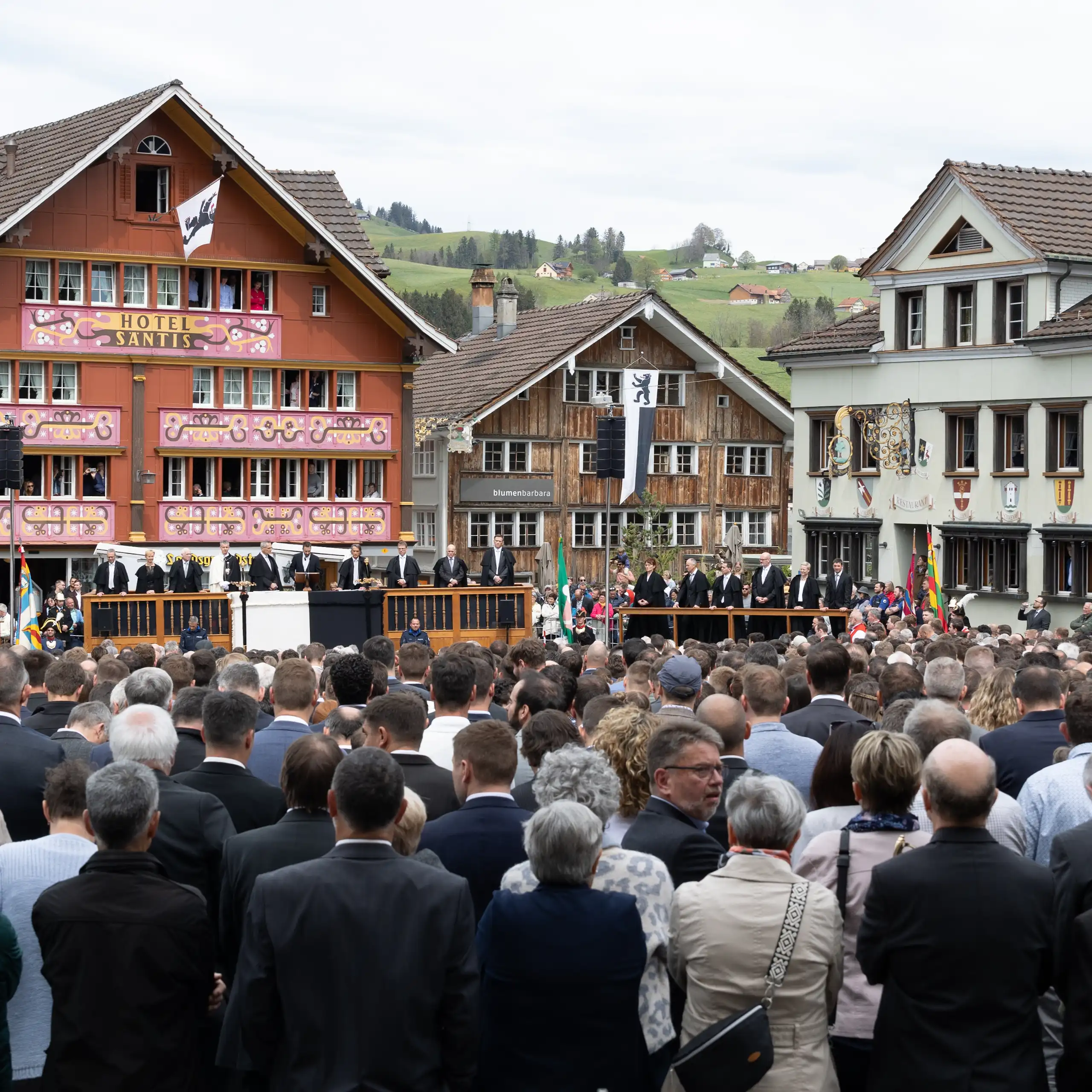 Foule assemblée sur une place, en arrière-plan, sur la tribune les conseillers du canton.