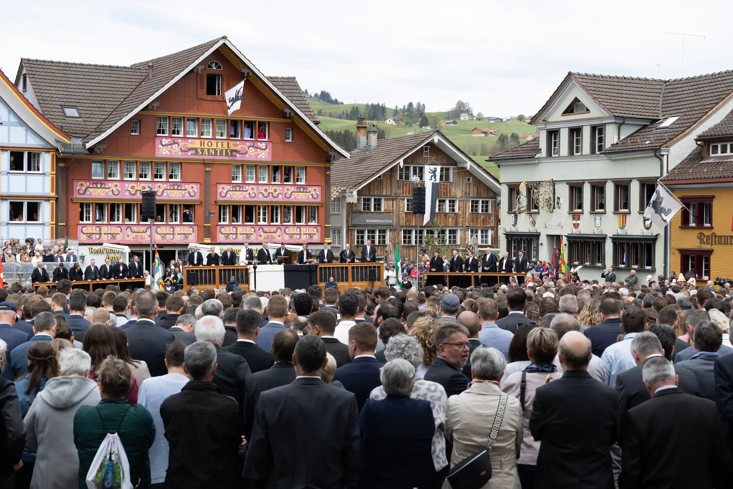Foule assemblée sur une place, en arrière-plan, sur la tribune les conseillers du canton.