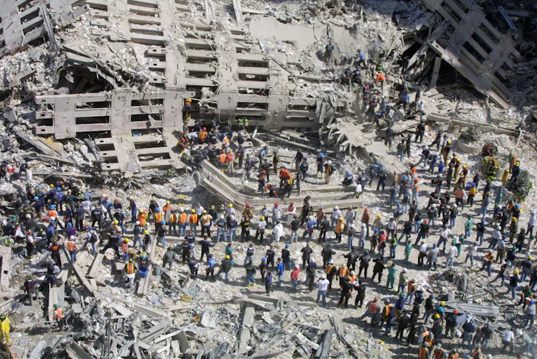 Aerial view of the wreckage of the World Trade Center, crowds of first responders attempting to rescue and recover survivors from the rubble