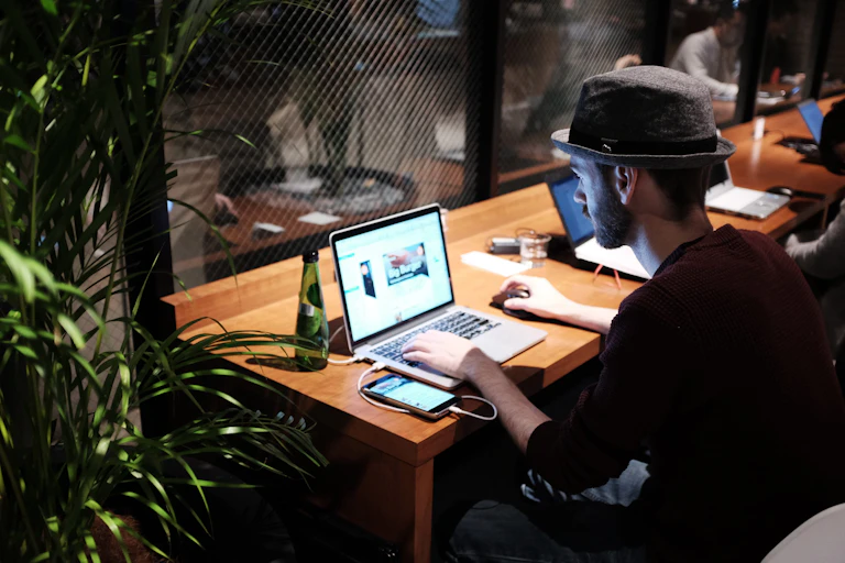 Young man sits at an office desk using a laptop at night