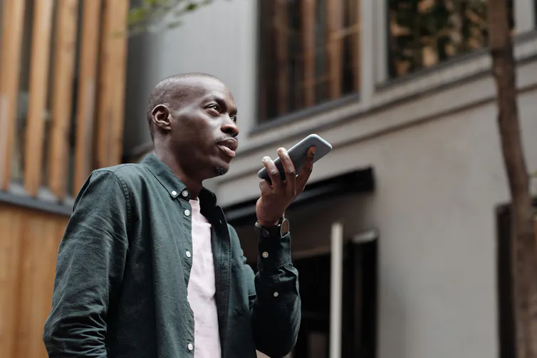 Man stands holding a phone in his hand and speaking into it