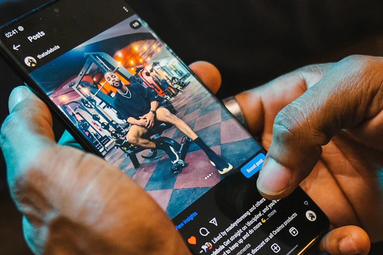 Close-up of hands browsing Instagram on smartphone with social media icons visible.