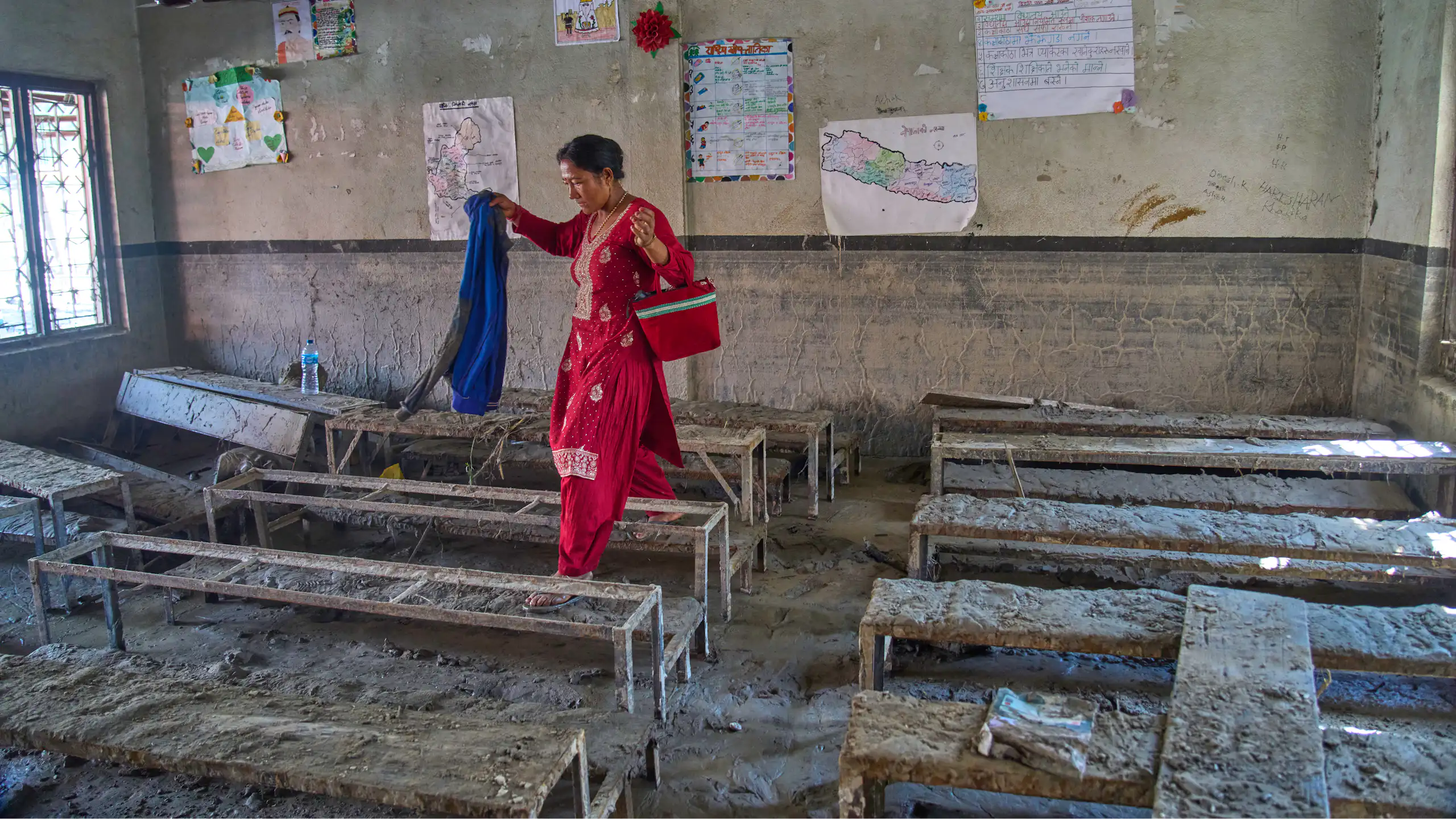 A woman picks up belongings inside a school damaged by the devastating Nepal-Tibet floods.