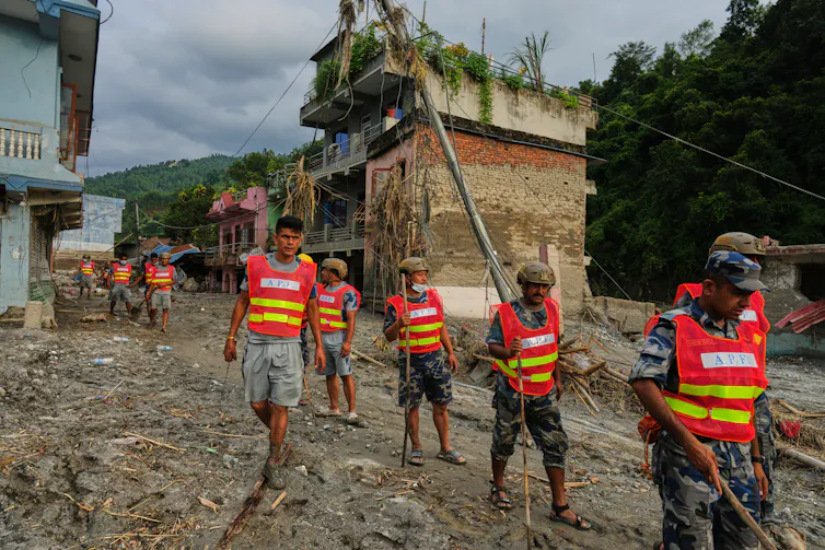 Workers in hi-vis vests clear debris in the aftermath of the Nepal-Tibet flash flood.