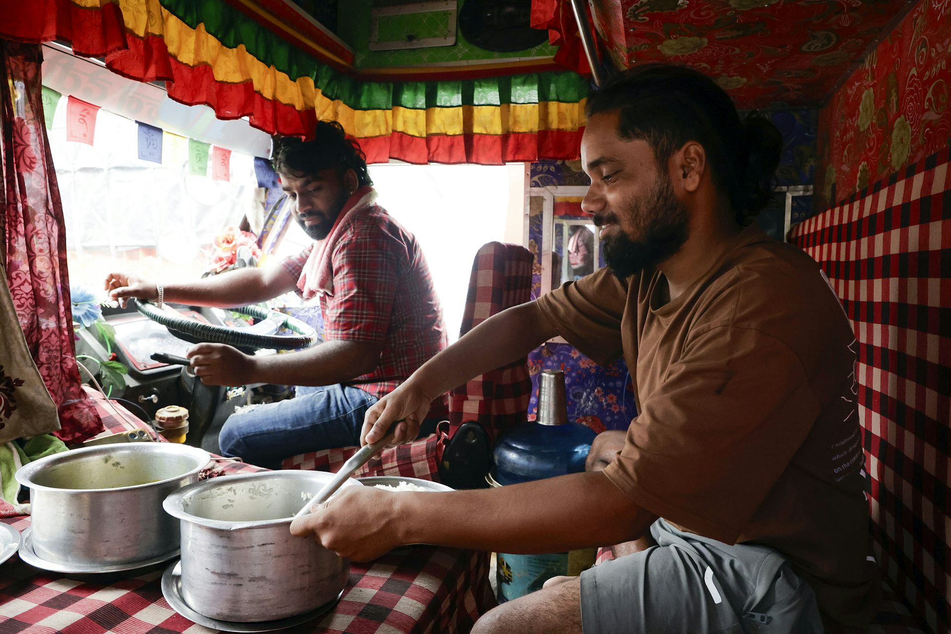 Two men prepare food in a truck after a flash flood.