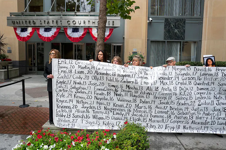 Family members hold a banner outside the courthouse in the Meta trial.
