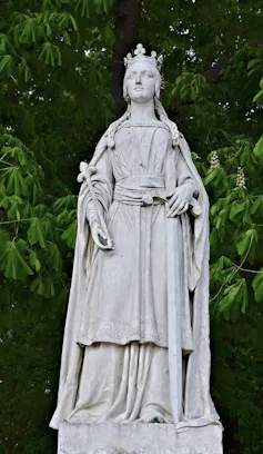 A marble statue of Matilda of Flanders with foliage in the background.