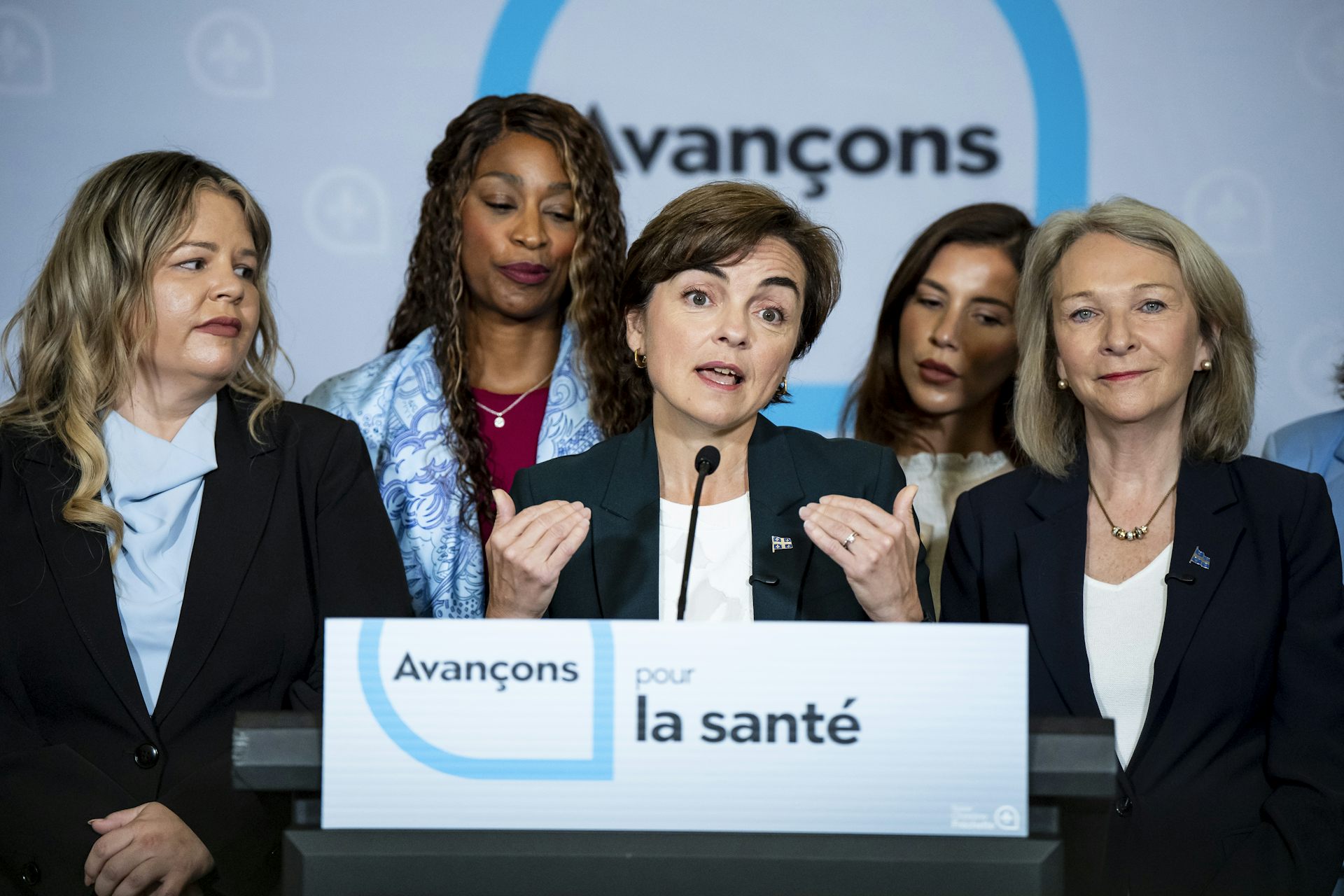 La cheffe de la CAQ Christine Fréchette en train de parler dans un micro, entouré de quatre femmes