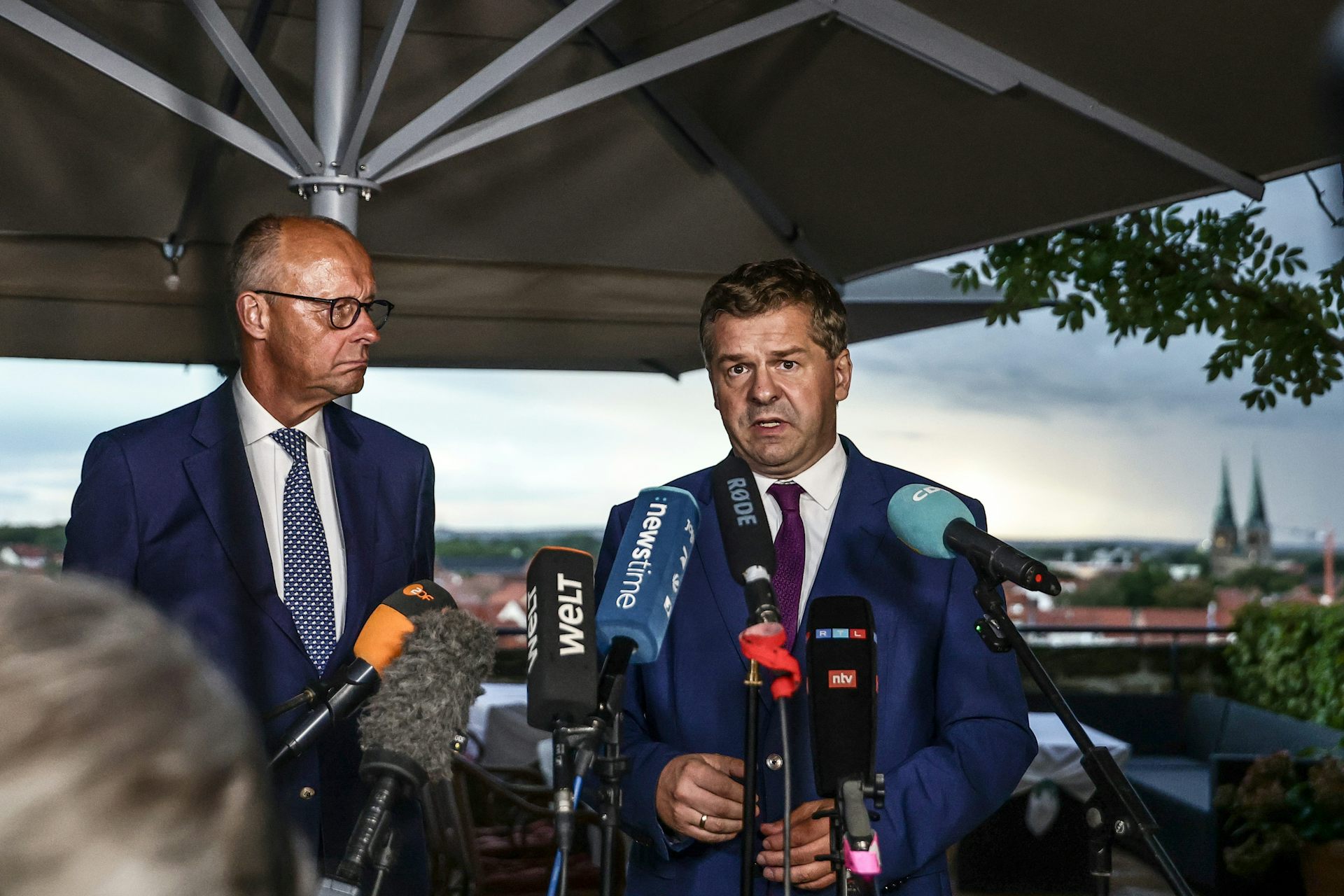 Friedrich Merz looks on as Sven Schulze speaks during a press conference.