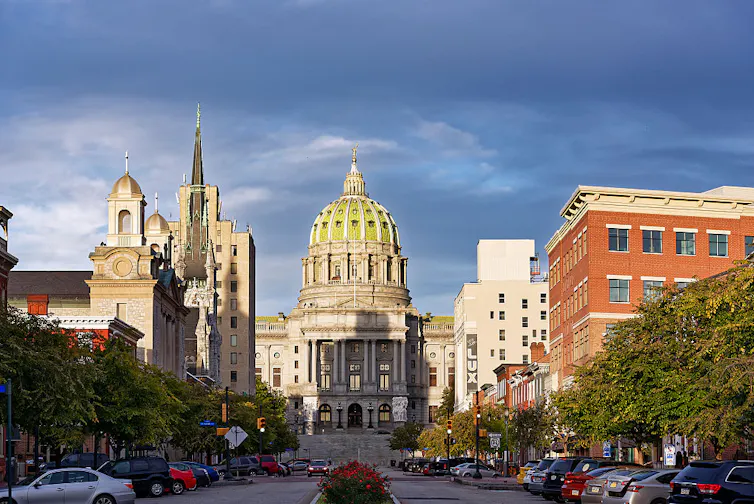 A large, ornate building sits at the end of a busy street.