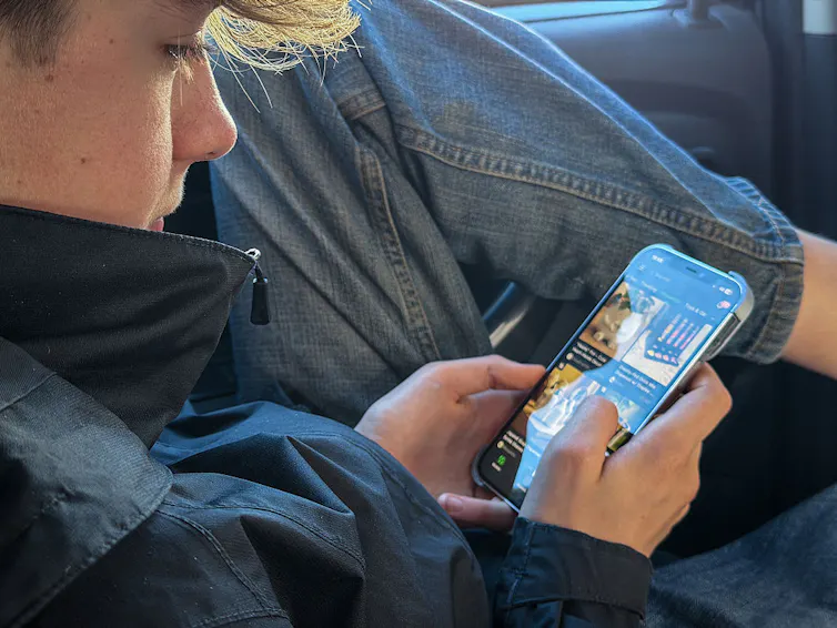 A teen boy is scrolling through videos on his phone.