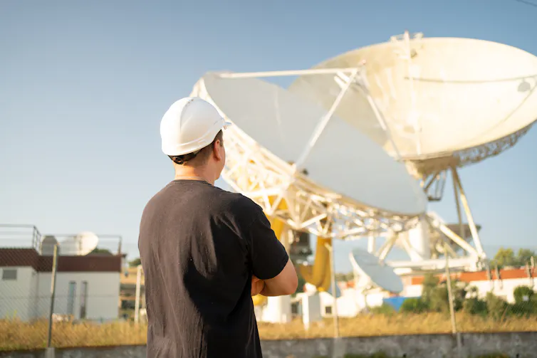 A man wearing a hard hat looking at two large telescope disks
