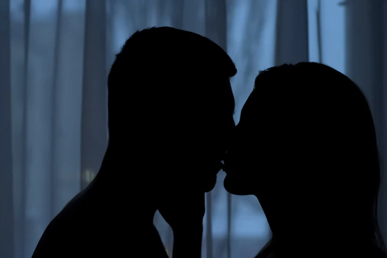 The silhouette of a couple kissing in the dark