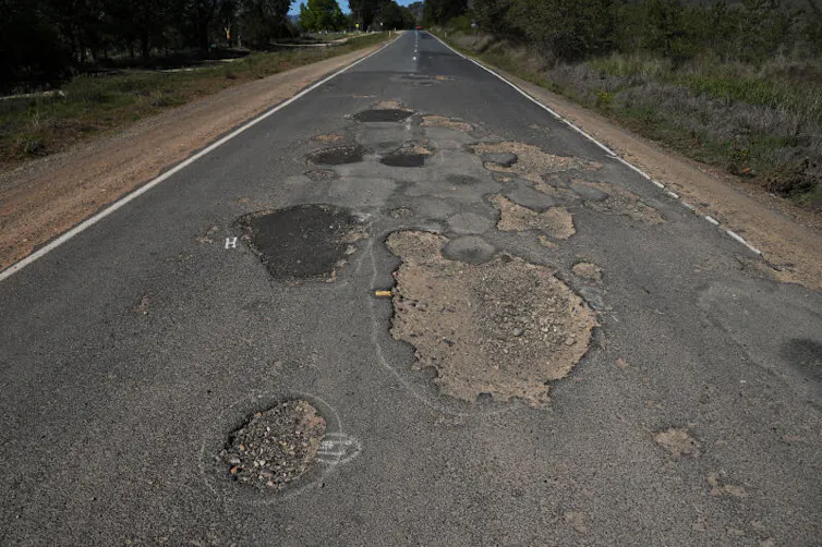 Pot holes are seen along a road in Walwa, Victoria.