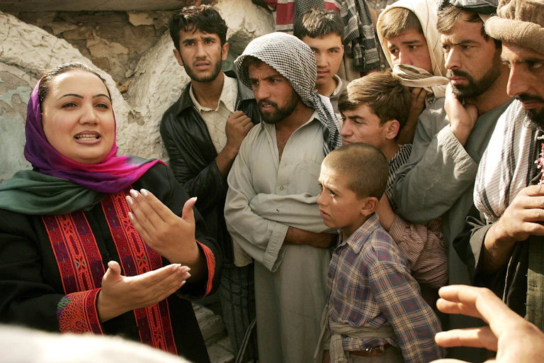 A female parliamentary candidate speaks to a group of men and boys in Afghanistan.