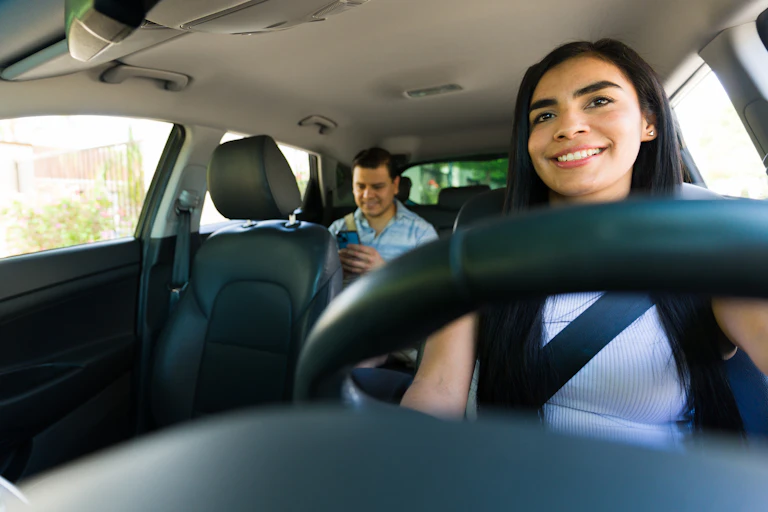 Mujer conduciendo con un pasajerón en el asiento trasero