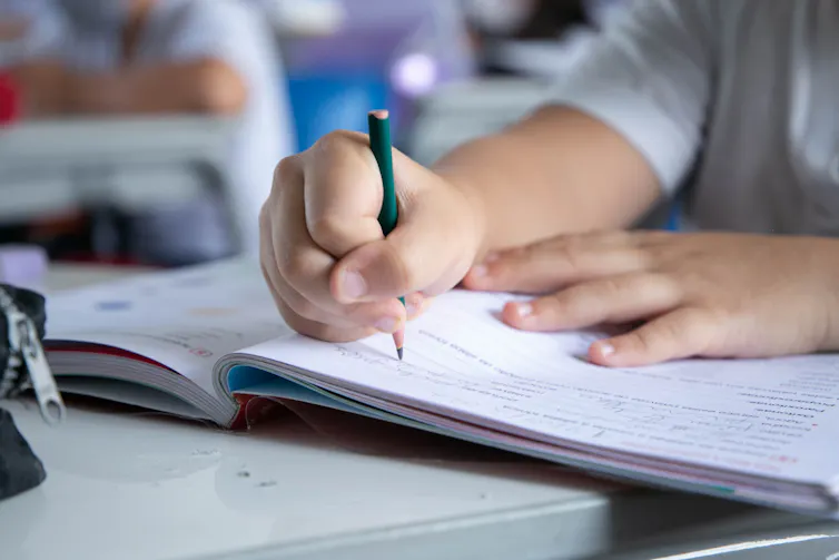Child's hand writing with pencil