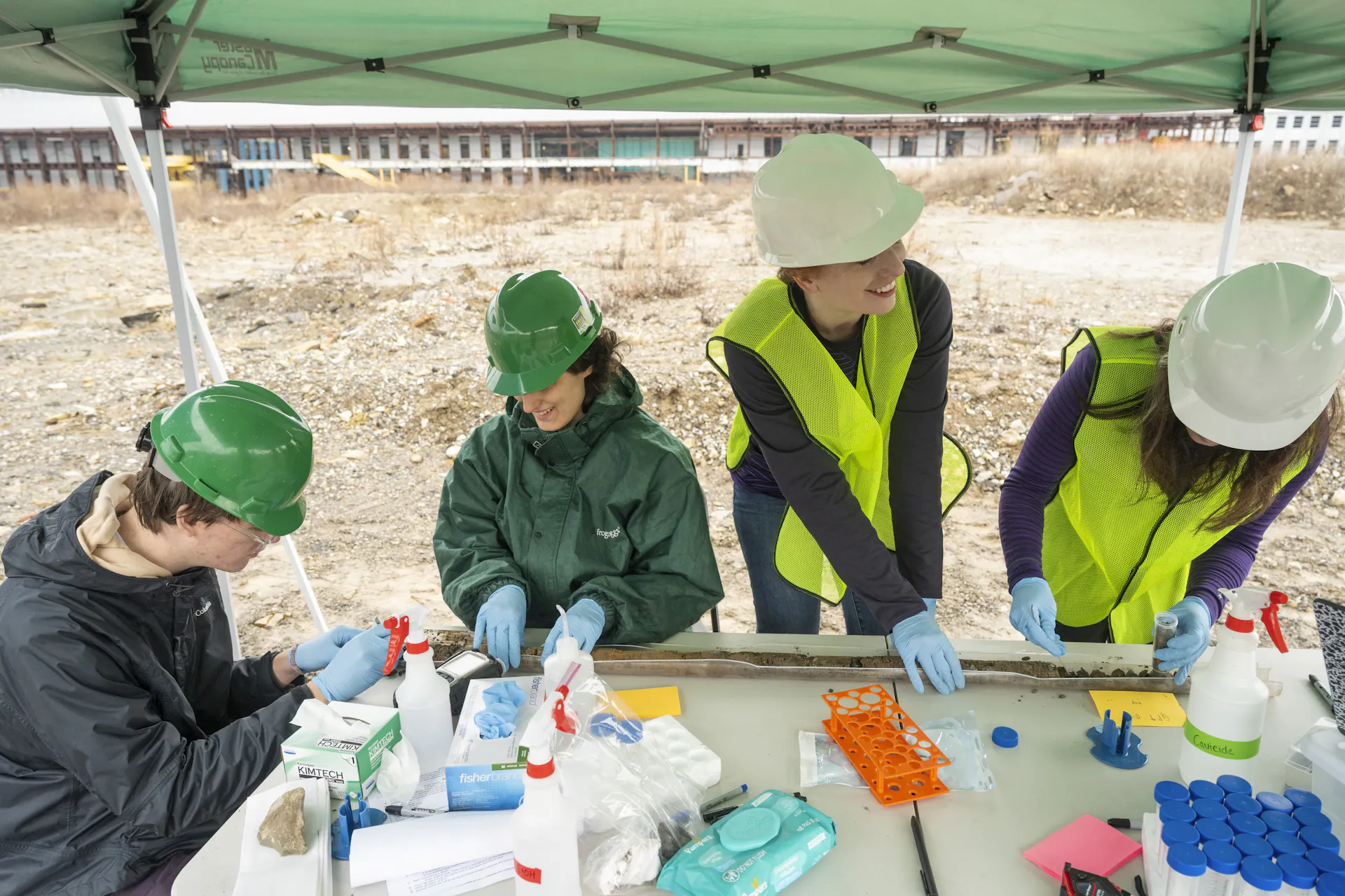 Four people work in an open field with scientific samples.