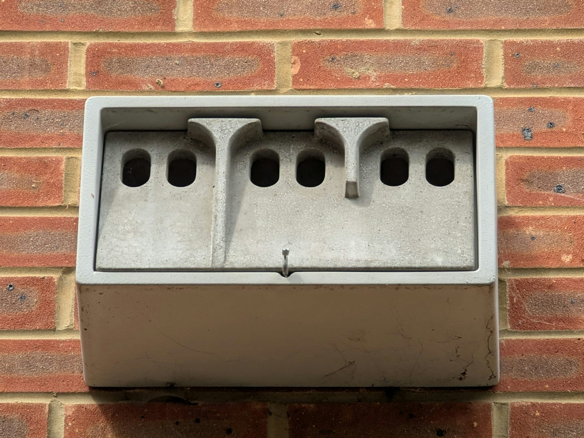 A concrete nesting box for birds, mounted on a brick wall.