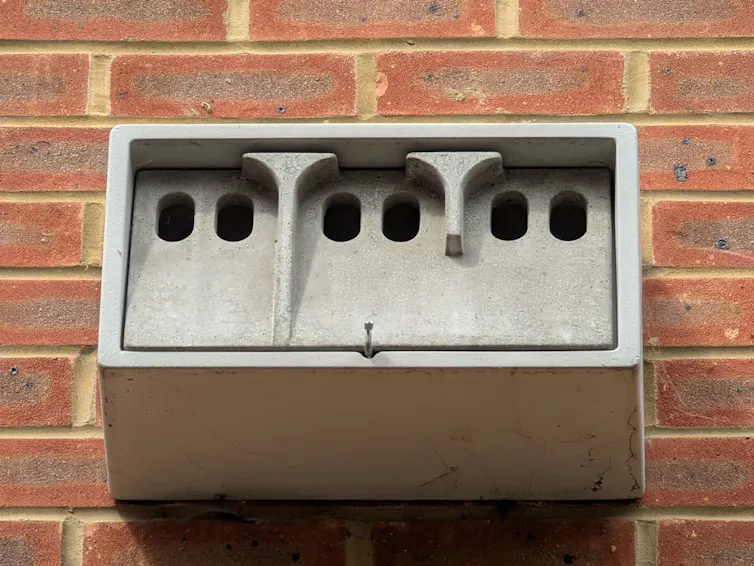 A concrete nesting box for birds, mounted on a brick wall.