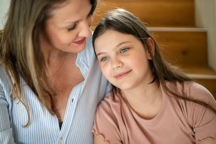 A girl and her mother sit on their stairs