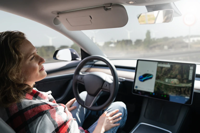 Generic image of a woman in the driver's seat of a self-driving car
