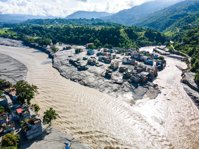 aerial view of flooded valley in nepal, green hillsides, grey water, flooded villages