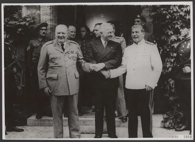US president, Harry Truman, joins hands with Winston Churchill and Josef Stalin.