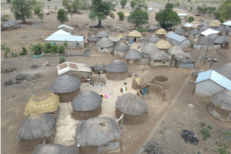 Aerial view of cluster of small buildings, mostly circular thatched mud structures