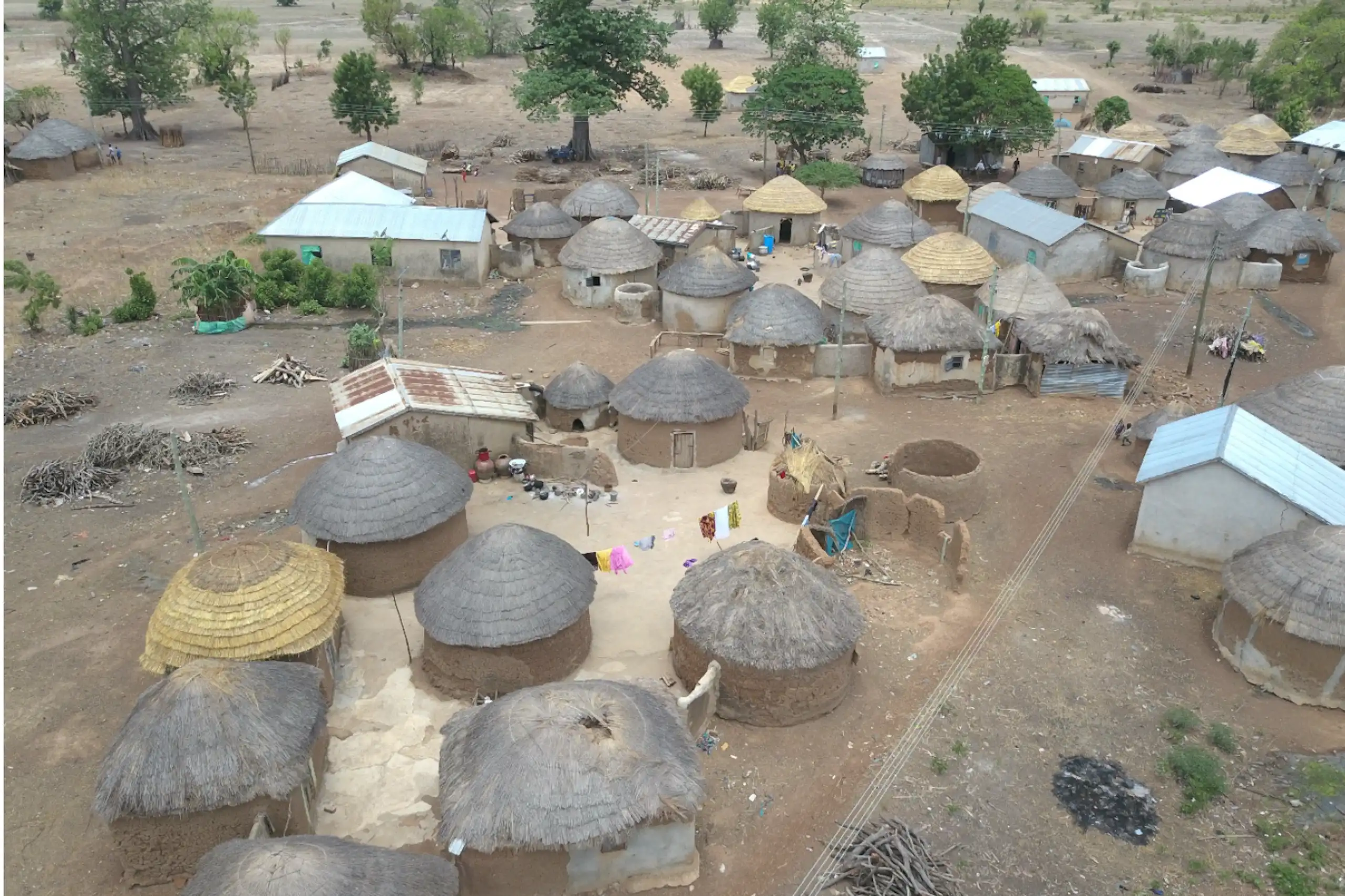 Aerial view of cluster of small buildings, mostly circular thatched mud structures
