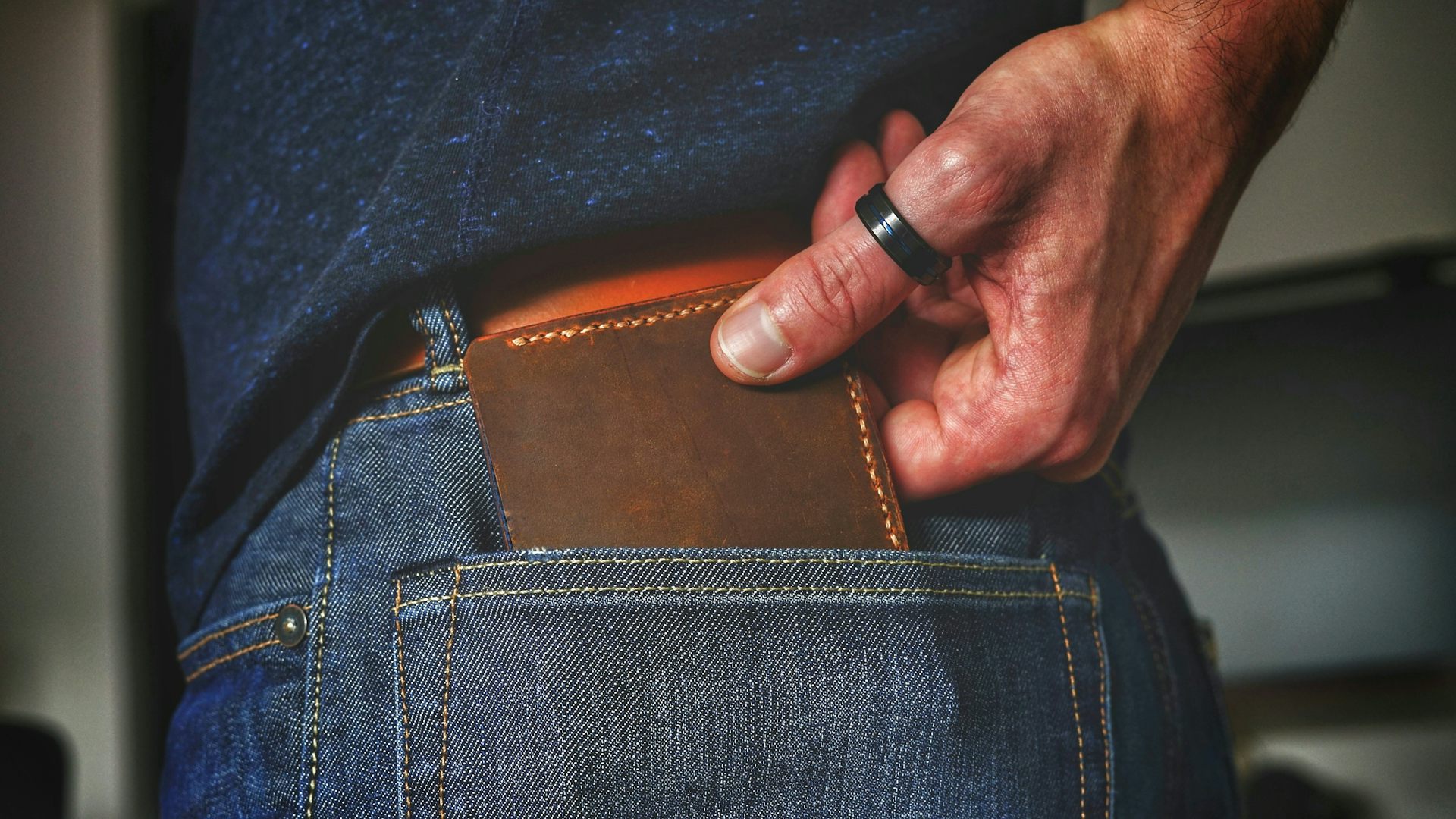 a hand pulls a wallet out of a jeans pocket