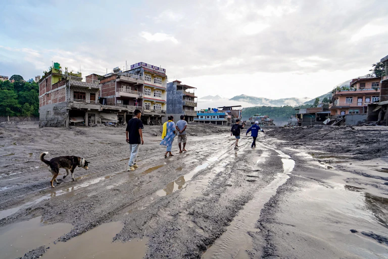People walking on muddy ruins of town in Nepal